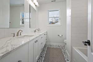 Bathroom featuring tile patterned floors, vanity, toilet, and backsplash