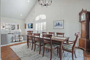 Dining area featuring dark hardwood / wood-style flooring, high vaulted ceiling, and a chandelier