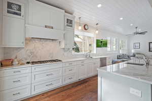 Kitchen with sink, appliances with stainless steel finishes, decorative light fixtures, dark hardwood / wood-style flooring, and white cabinetry