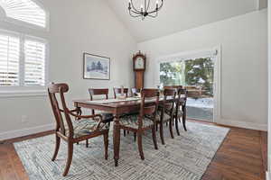 Dining room with high vaulted ceiling, an inviting chandelier, and dark wood-type flooring