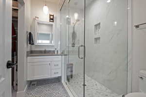 Bathroom with a shower with door, vanity, and toilet