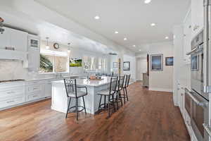 Kitchen featuring a breakfast bar area, dark hardwood / wood-style flooring, white cabinets, and a kitchen island