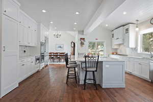 Kitchen with white cabinets, dark hardwood / wood-style flooring, a kitchen island, and a wealth of natural light