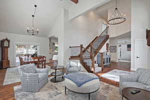 Living room featuring dark wood-type flooring, high vaulted ceiling, and a chandelier