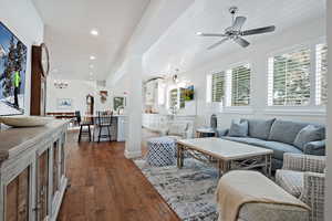 Living room with ceiling fan with notable chandelier, dark wood-type flooring, and wood ceiling