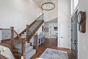 Entrance foyer with a chandelier, dark hardwood / wood-style flooring, and a towering ceiling