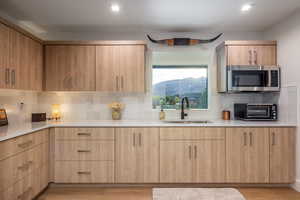 Kitchen with a mountain view, light brown cabinets, sink, and light hardwood / wood-style flooring