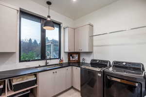 Laundry area with cabinets, sink, and washing machine and clothes dryer