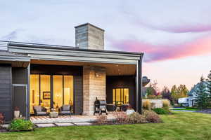 Back house at dusk with a patio area and a yard