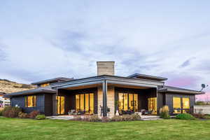 Rear view of house featuring a lawn, an outdoor living space, and a patio