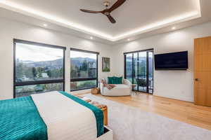 Bedroom featuring hardwood / wood-style flooring, a raised ceiling, and ceiling fan