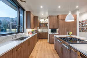 Kitchen with light wood-type flooring, sink, decorative light fixtures, a mountain view, and stainless steel gas stovetop