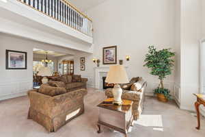 Living room with light carpet, a towering ceiling, and a fireplace