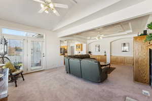 Carpeted living room featuring ceiling fan, lofted ceiling, and crown molding