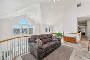 Living room with high vaulted ceiling and ceiling fan with notable chandelier