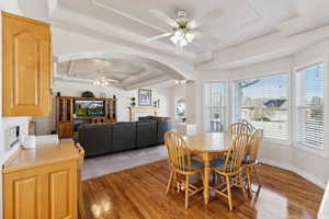 Dining area featuring a tray ceiling, ceiling fan, crown molding, and wood-type flooring