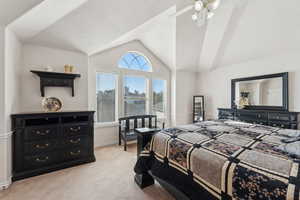 Carpeted bedroom featuring a textured ceiling, ceiling fan, and vaulted ceiling