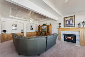 Living room featuring ceiling fan, a premium fireplace, light carpet, and ornamental molding