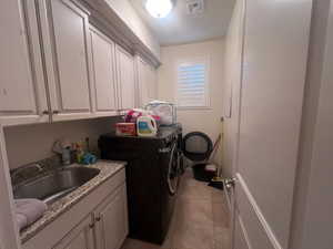 Laundry area with cabinets, light tile patterned floors, washer and clothes dryer, and sink