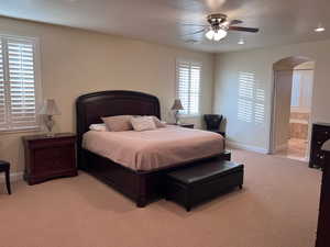 Bedroom featuring ceiling fan, light carpet, and connected bathroom