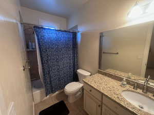 Full bathroom featuring tile patterned flooring, shower / bath combo, toilet, and vanity