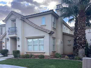 View of front of home with a balcony and a front lawn