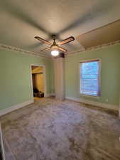 Unfurnished bedroom featuring ceiling fan, carpet, and a textured ceiling