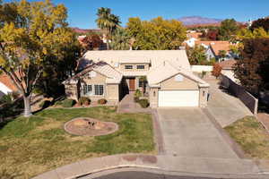 View of front of property featuring a mountain view, a front lawn, and a garage