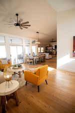 Living room featuring ceiling fan with notable chandelier and light hardwood / wood-style flooring