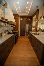 Kitchen featuring light stone counters, stainless steel appliances, sink, decorative light fixtures, and light hardwood / wood-style floors