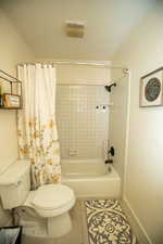 Bathroom with tile patterned floors, shower / bath combo, and toilet