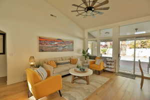 Living room featuring ceiling fan, high vaulted ceiling, and light wood-type flooring