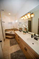 Bathroom with tile patterned flooring, vanity, and tiled tub