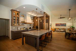 Kitchen with pendant lighting, ceiling fan, light hardwood / wood-style floors, and light stone counters