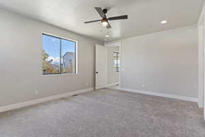 Unfurnished room featuring ceiling fan, light colored carpet, and a textured ceiling