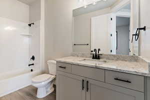 Full bathroom with hardwood / wood-style floors, vanity, toilet, and shower / washtub combination