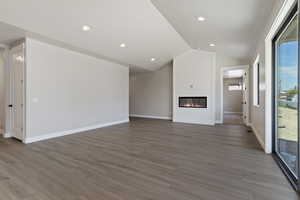 Unfurnished living room with light hardwood / wood-style floors, lofted ceiling, a fireplace, and a wealth of natural light