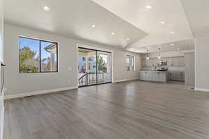 Unfurnished living room with plenty of natural light, light hardwood / wood-style floors, lofted ceiling, and sink