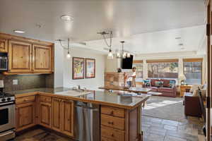 Kitchen with backsplash, hanging light fixtures, sink, appliances with stainless steel finishes, and kitchen peninsula