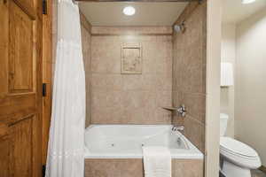 Bathroom featuring toilet and shower / bath combo with shower curtain