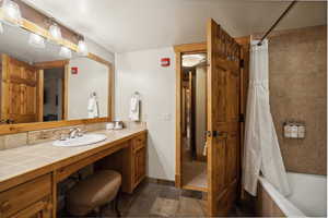 Bathroom featuring tile patterned flooring, shower / bath combination with curtain, and vanity