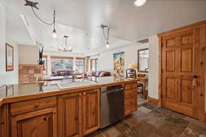 Kitchen with dishwasher, kitchen peninsula, tile counters, and sink