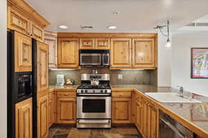 Kitchen featuring backsplash, sink, stainless steel appliances, and decorative light fixtures