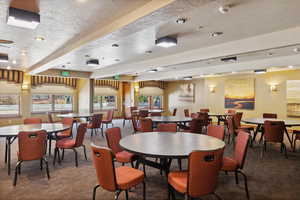 Carpeted dining room with beamed ceiling and a textured ceiling