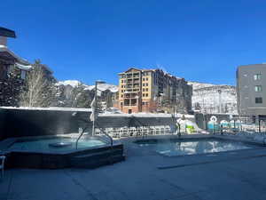 Snow covered pool with a mountain view and a hot tub