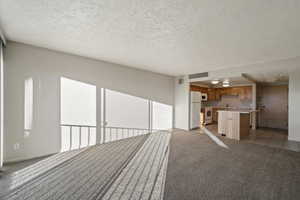 Unfurnished living room with a textured ceiling and light carpet