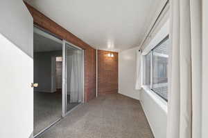 Interior space featuring carpet, a textured ceiling, and brick wall