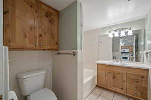 Bathroom with a tub, ceiling fan, tile patterned floors, toilet, and vanity