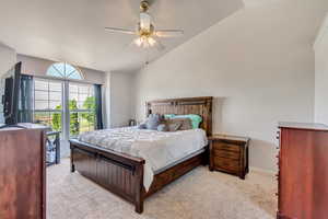 Carpeted bedroom featuring ceiling fan and vaulted ceiling