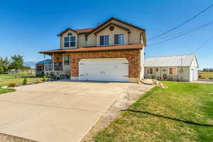 View of front of property with covered porch, a garage, and a front lawn